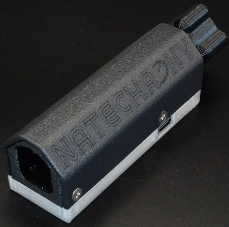 Close-up of the NateChrony v2.5 device, featuring a sleek black design with engraved branding, displayed on a dark background, highlighting its precision and craftsmanship.