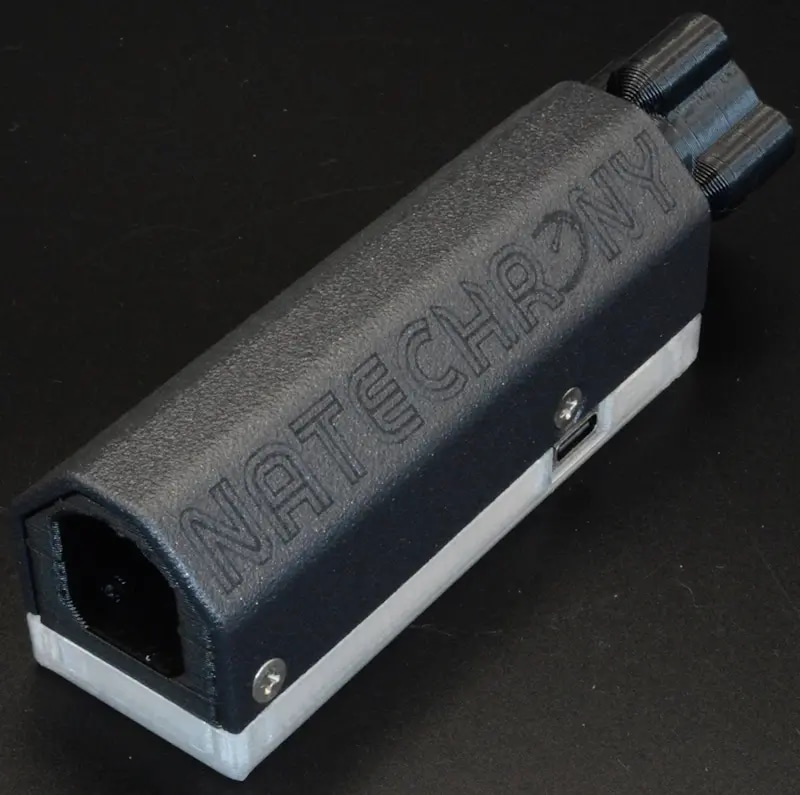 Close-up of the NateChrony v2.5 device, featuring a sleek black design with engraved branding, displayed on a dark background, highlighting its precision and craftsmanship.